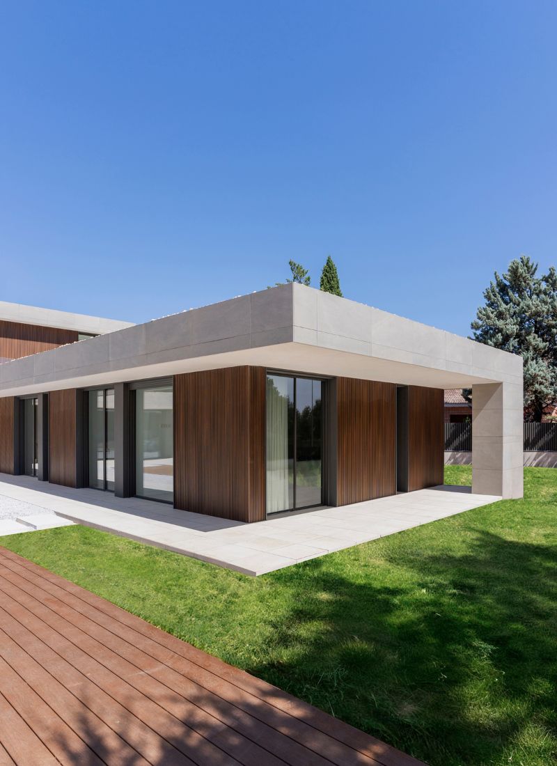 Porche con porcelánico gris y madera tecnológica en casa en forma de L en Madrid