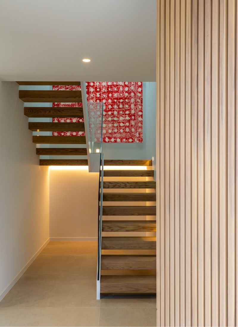 Escaleras de madera iluminadas con barandilla cristal