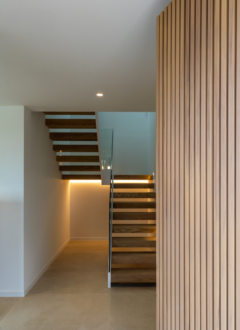 Escaleras de madera iluminadas con barandilla cristal