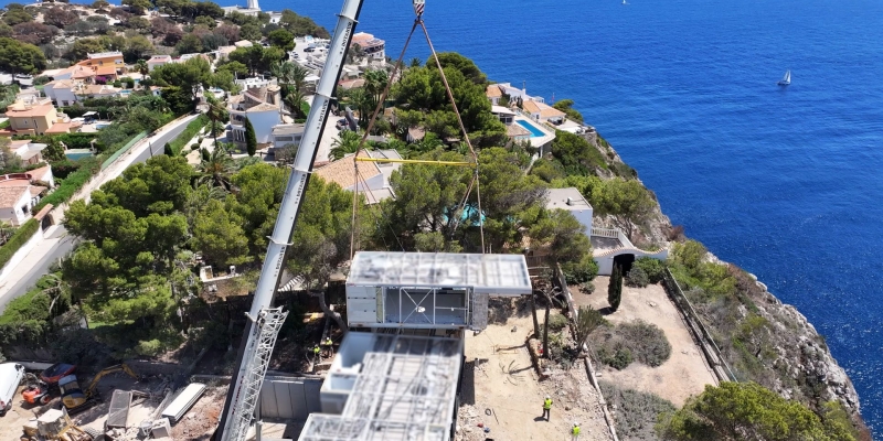 Módulo de una casa industrializada levantado por una grúa en el aire para construir